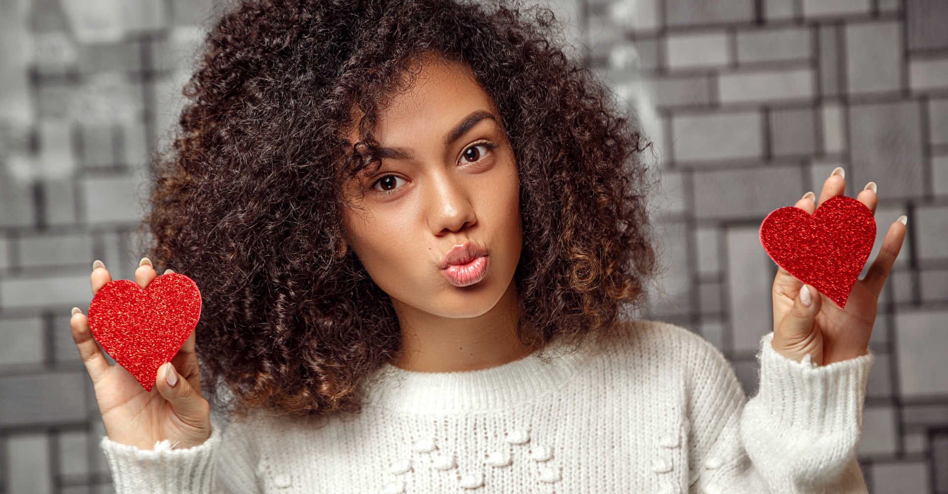 Modelo negra com dois corações vermelhos na mão